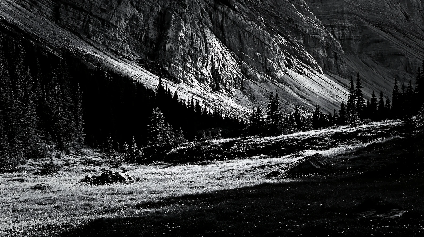 Meadow under crags with trees and mountainous backdrop - AI-generated stock image