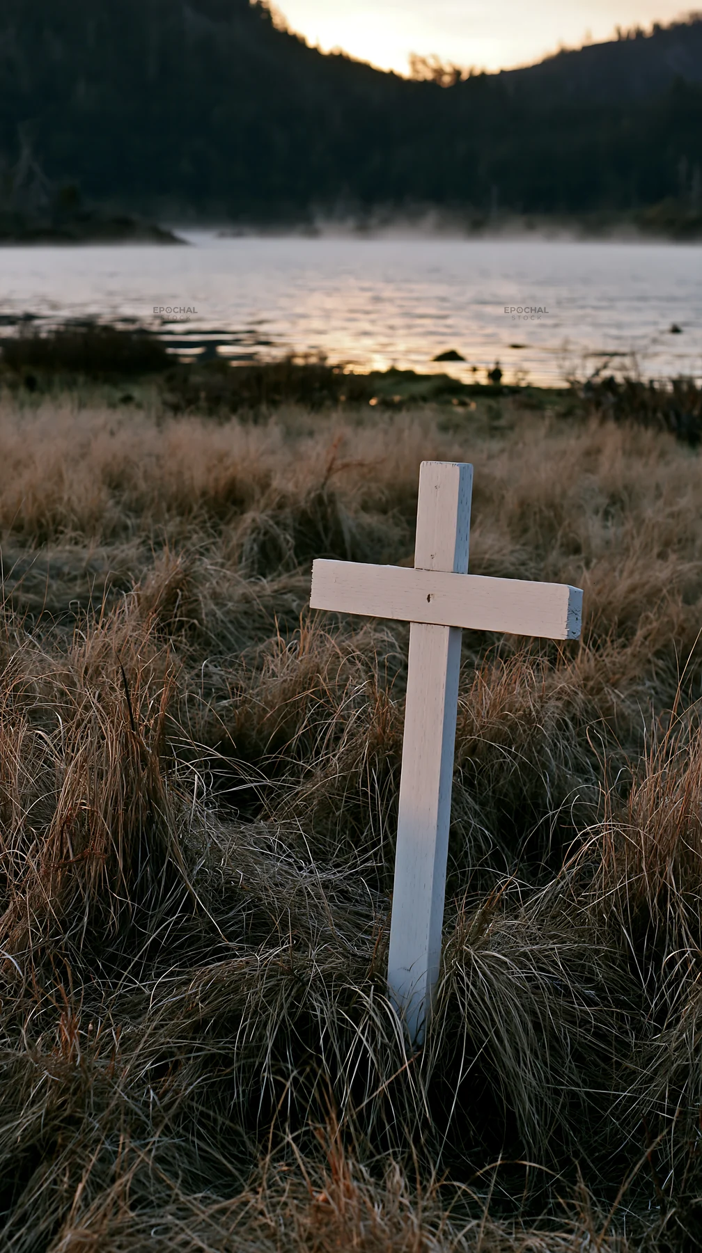 White Christian cross in the meadow by the water - AI-generated stock image
