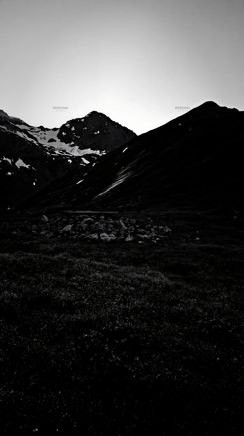 Meadow with crepuscular rays and mountains at dusk - AI-generated stock image