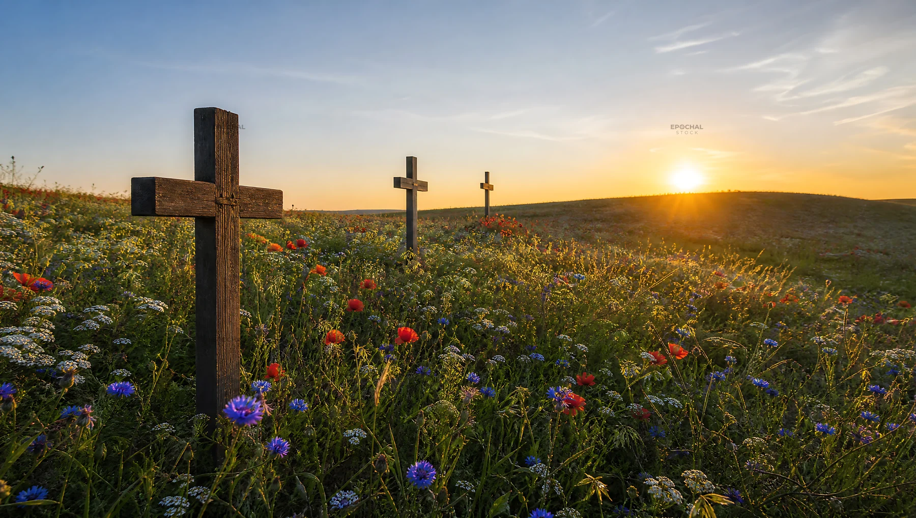 Christian crosses on meadow during sunrise with light rays - AI-generated stock image