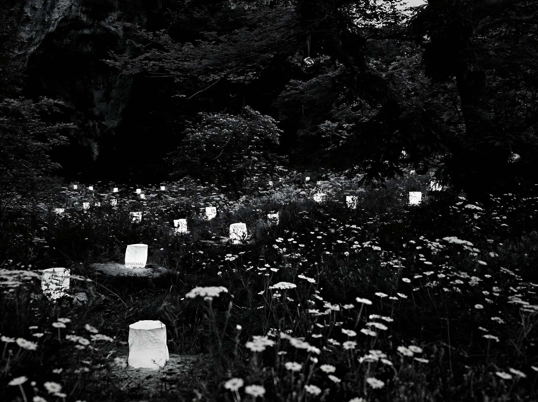 Christmas lanterns at dusk in meadow by cave - AI-generated stock image