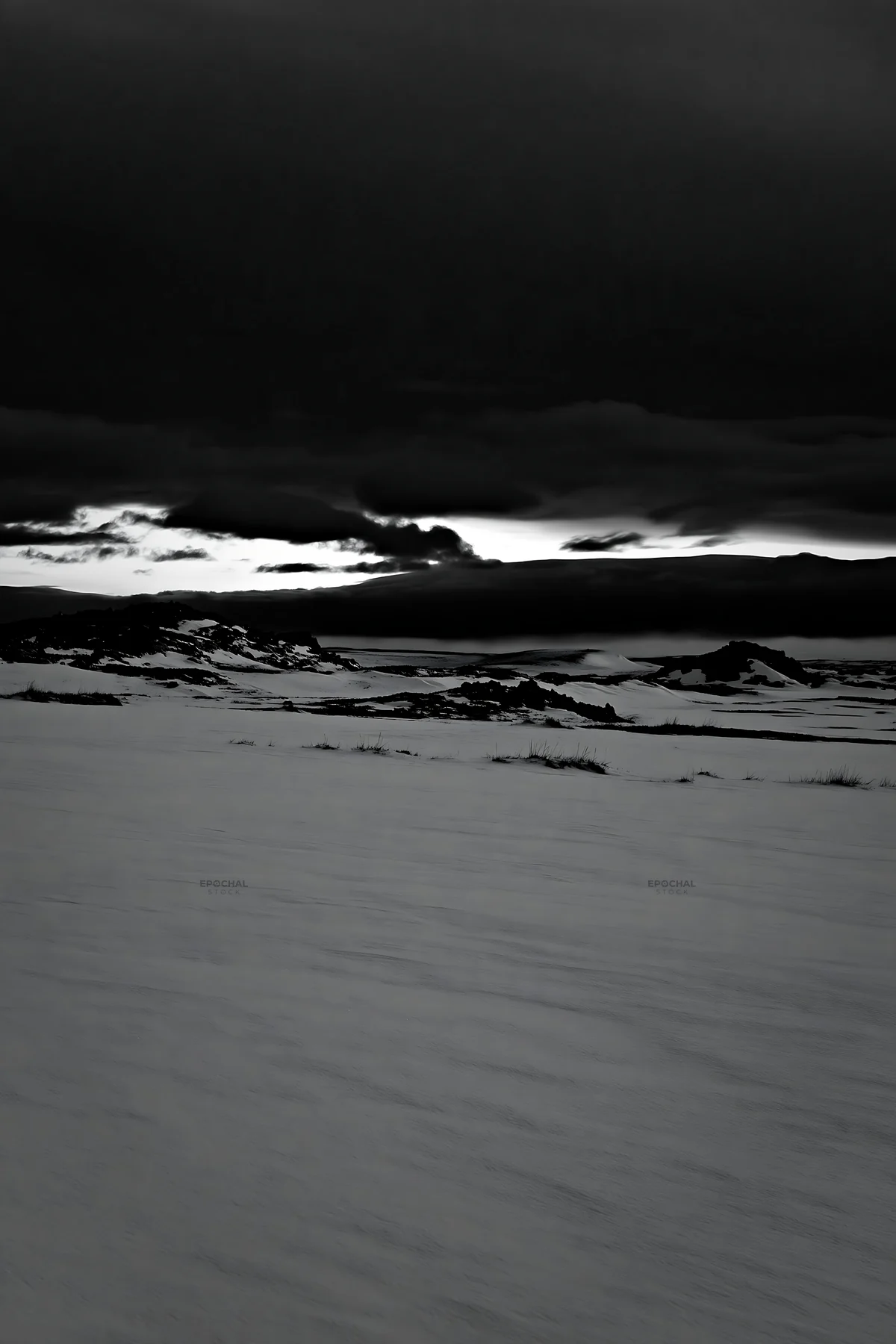 Snowbound meadow under dark clouds at twilight - AI-generated stock image