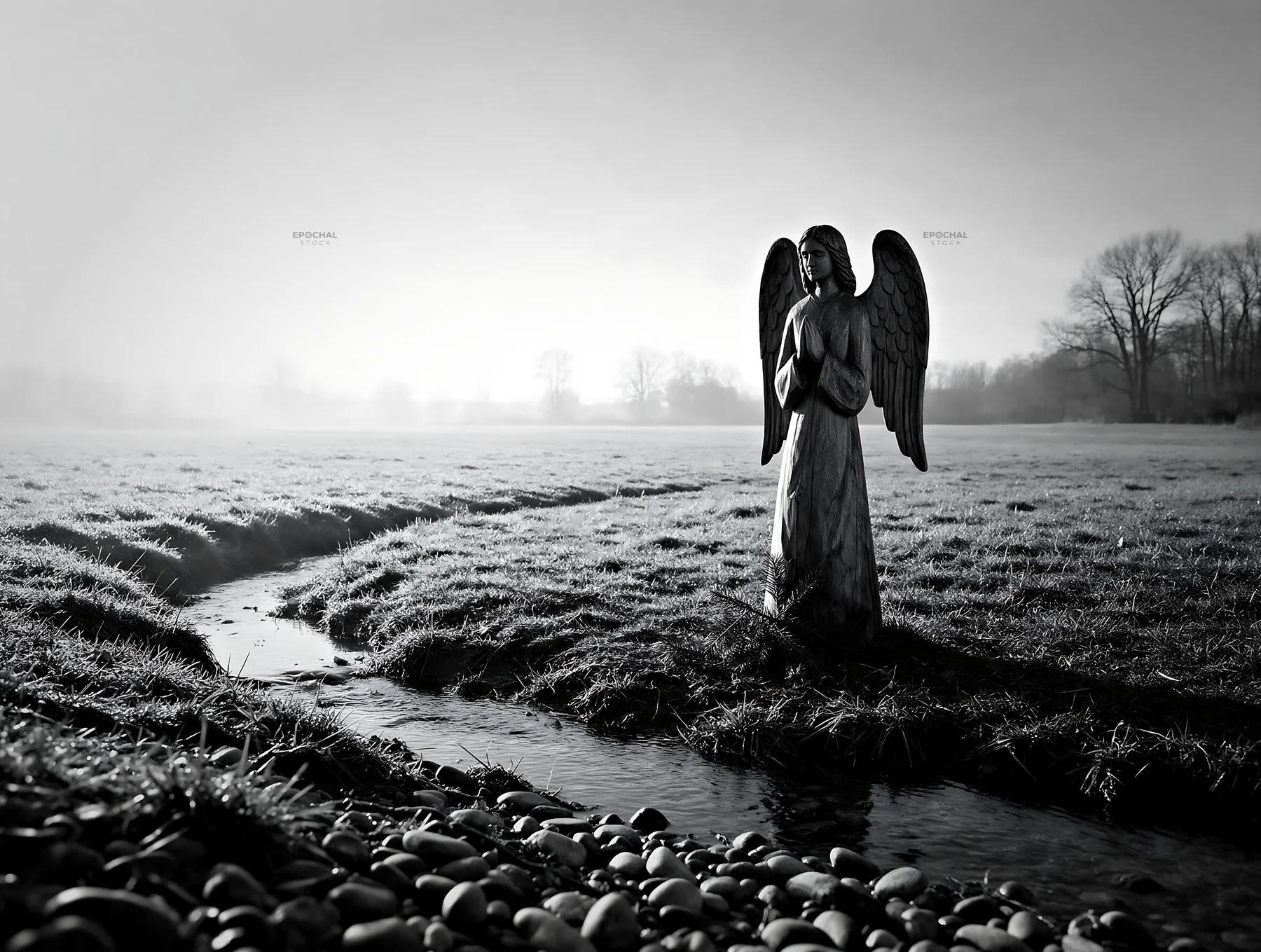 Wooden angel stands in a meadow near a creek