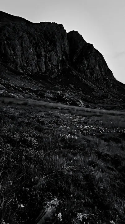 Meadow beneath jagged crags at dusk - AI-generated stock image