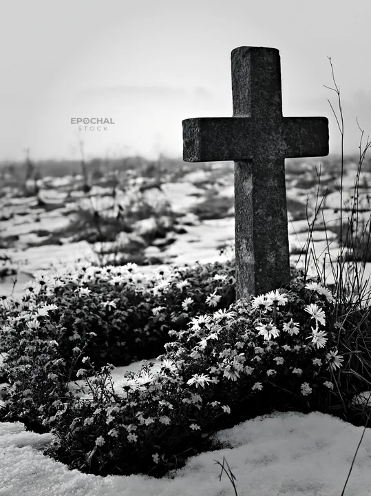 Stone Christian cross in snowy meadow with flowers - AI-generated stock image