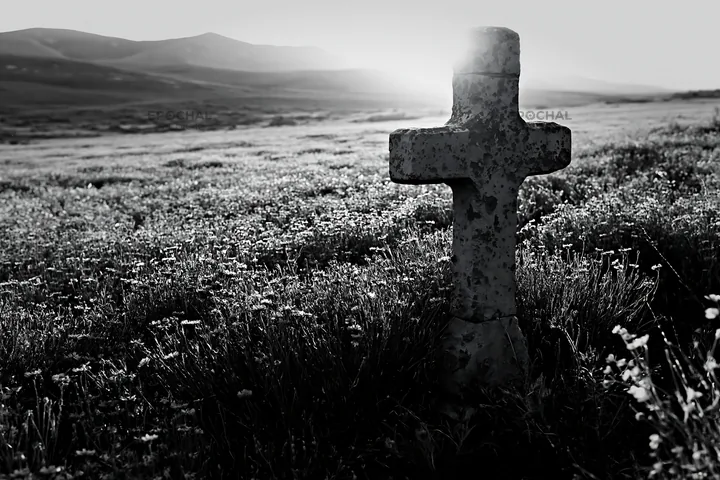 Christian cross in backlit summer meadow with mountains in view - AI-generated stock image