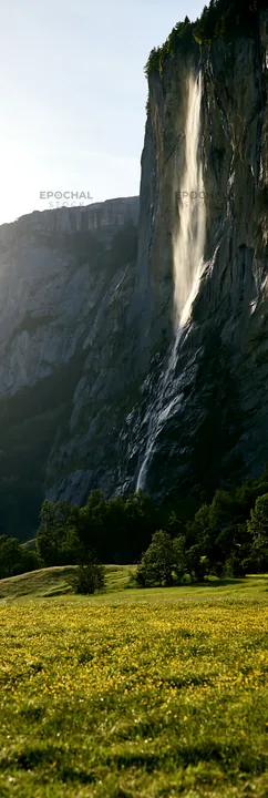 Lauterbrunnen Valley meadow with light rays and waterfall - AI-generated stock image