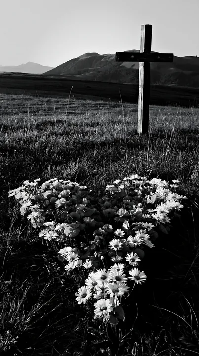 Christian cross in meadow at sunrise with flowers - AI-generated stock image