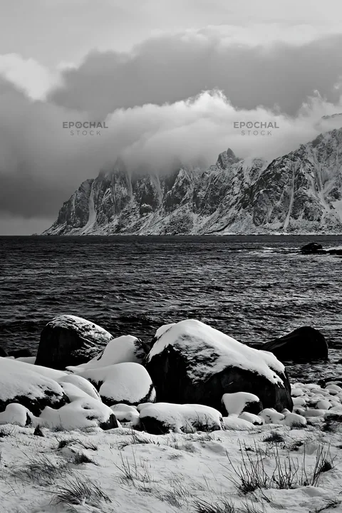 Black and white lofoten coastal meadow winter snow with rocky shoreline - AI-generated stock image
