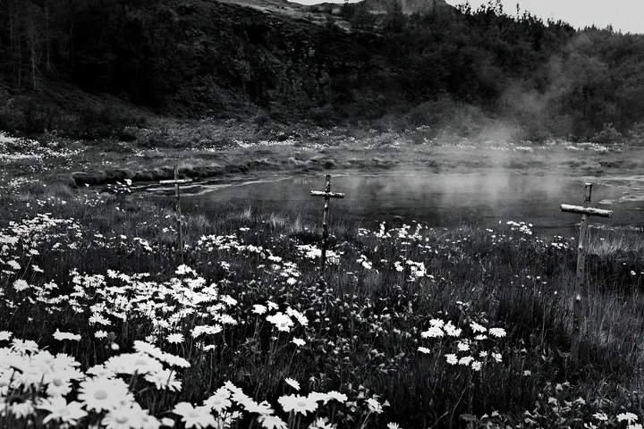 Christian crosses surrounded by flowers near geothermal spring - AI-generated stock image
