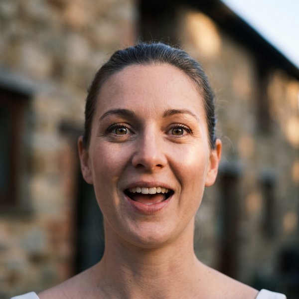 Woman smiles in front of a stone building during sunset - stock photo
