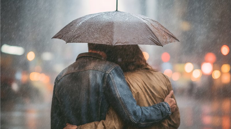 Couple shares an umbrella in the rain on a city street Free Premium Stock Image - stock photo