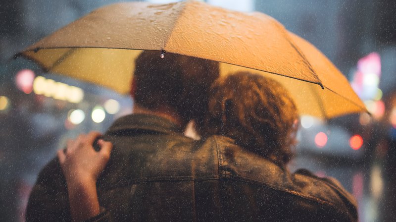 Couple sharing an umbrella on a rainy city street Free Premium Stock Photo - stock photo