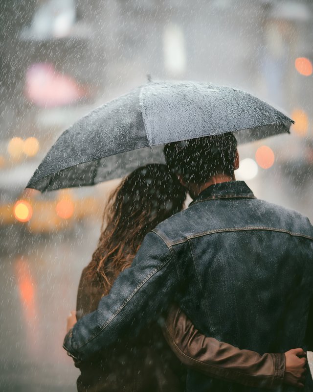 Couple sharing an umbrella on a rainy day in the city Free Premium Stock Photo - stock photo