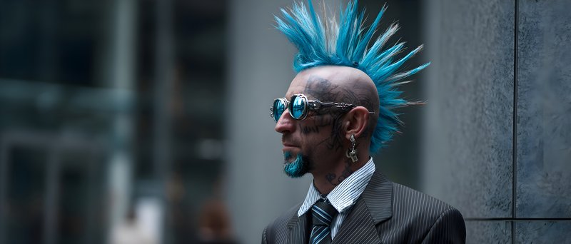Punk man with blue hair and sunglasses stands in the city Free Premium Stock Image - stock photo