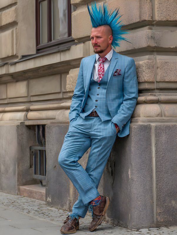 Man with blue hair stands against building in city Free Premium Stock Photo - stock photo