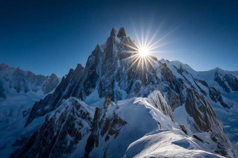 Bright sun rising over snowy mountain peak with sharp rocks Free Premium Stock Photo - stock photo