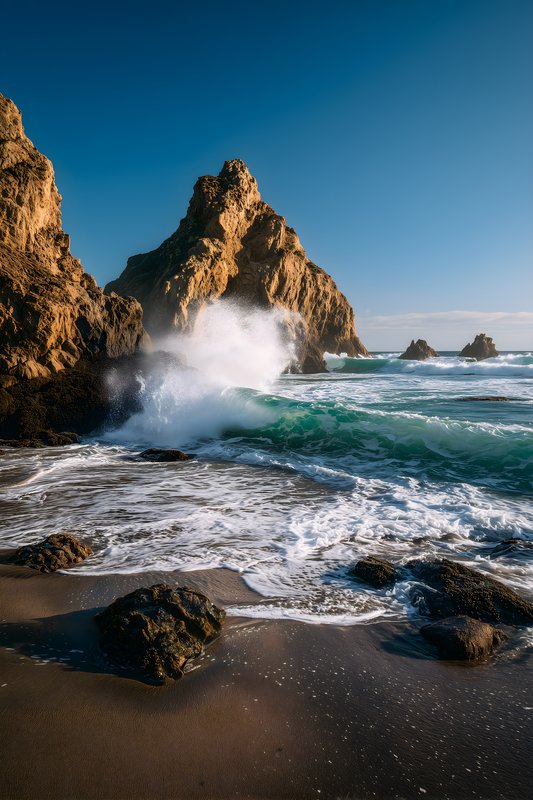 Waves crash on rocks beside a mountain by the beach Free Premium Stock Image - stock photo