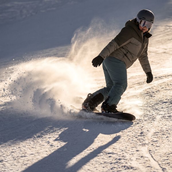 Snowboarder rides on snowy slope during winter in mountain area - stock photo