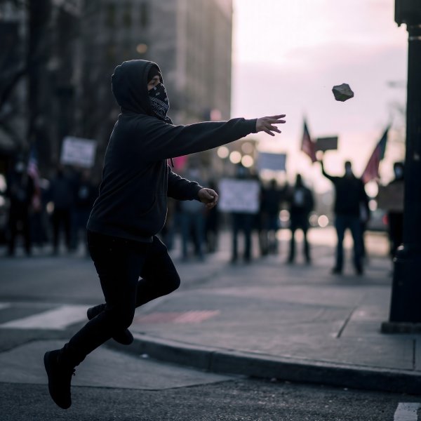 Protester throws a rock during a demonstration in the city - stock photo