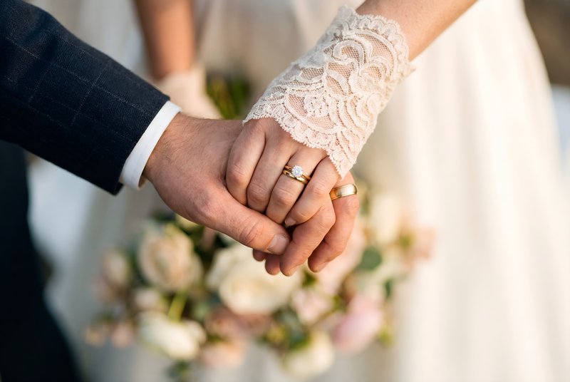 Couple holds hands during wedding ceremony with bouquet Premium Stock Photo - stock photo