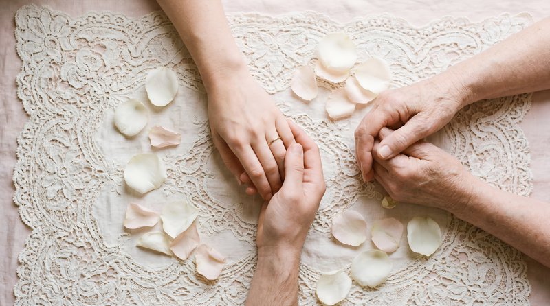 Hands holding each other with rose petals on lace fabric Premium Stock Photo - stock photo