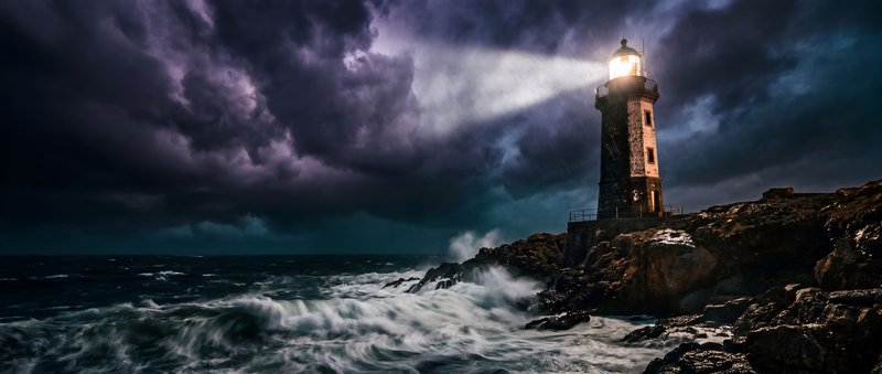 Lighthouse shines light during stormy night at sea Premium Stock Photo - stock photo