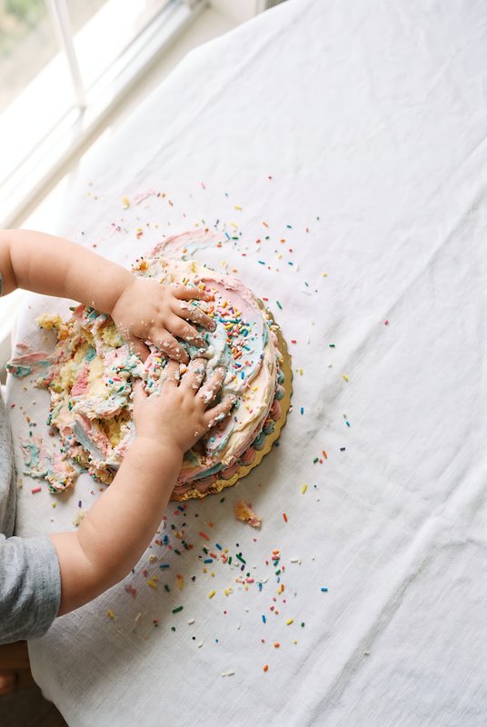 Child plays with cake on a table in bright room Premium Stock Image - stock photo