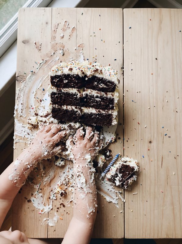 Child enjoys cake with hands at home on a wooden table Premium Stock Photo - stock photo