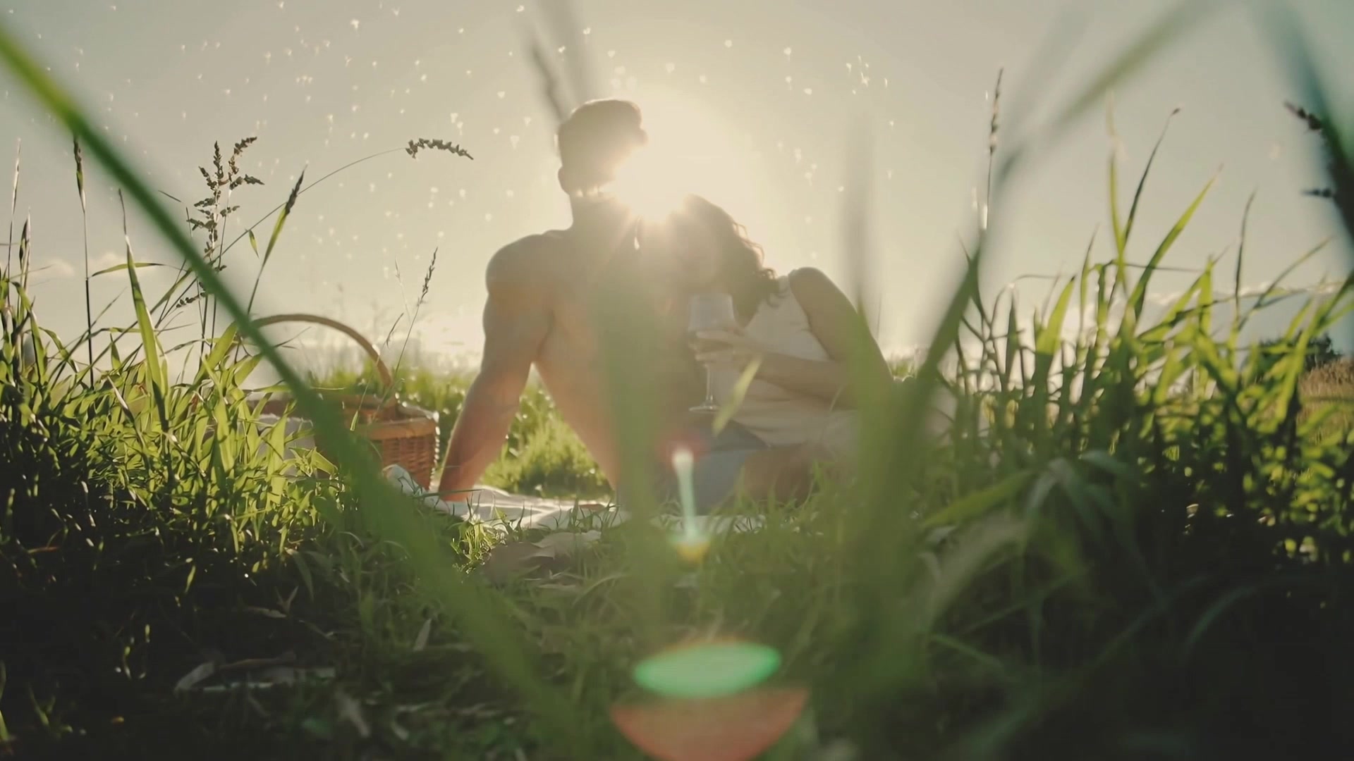 Couple enjoys picnic in nature during golden hour while surrounded by grass and sunlight in a relaxed atmosphere - stock video