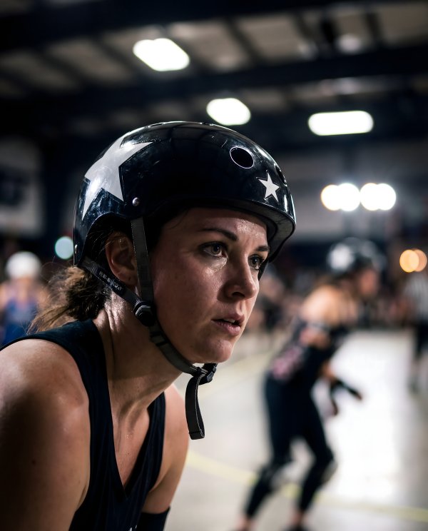 Woman wearing helmet prepares for roller derby match indoors - stock photo