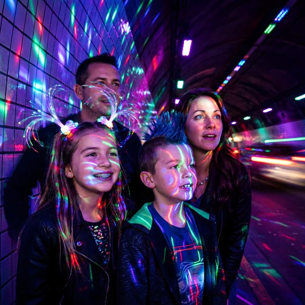 Family enjoys colorful light display in urban tunnel at night - stock photo