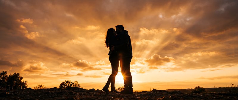 Couple embraces during sunset on a hilltop Premium Stock Image - stock photo