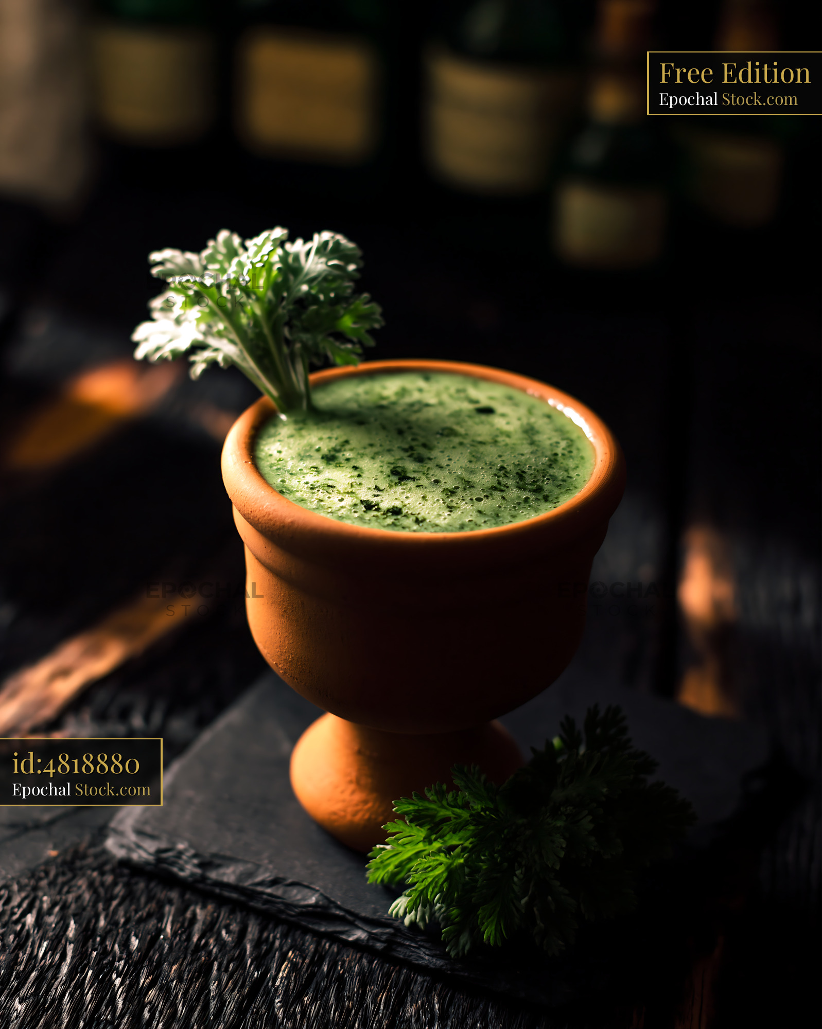 Green mugwort herb smoothie in a rustic clay cup on a dark table - stock photo