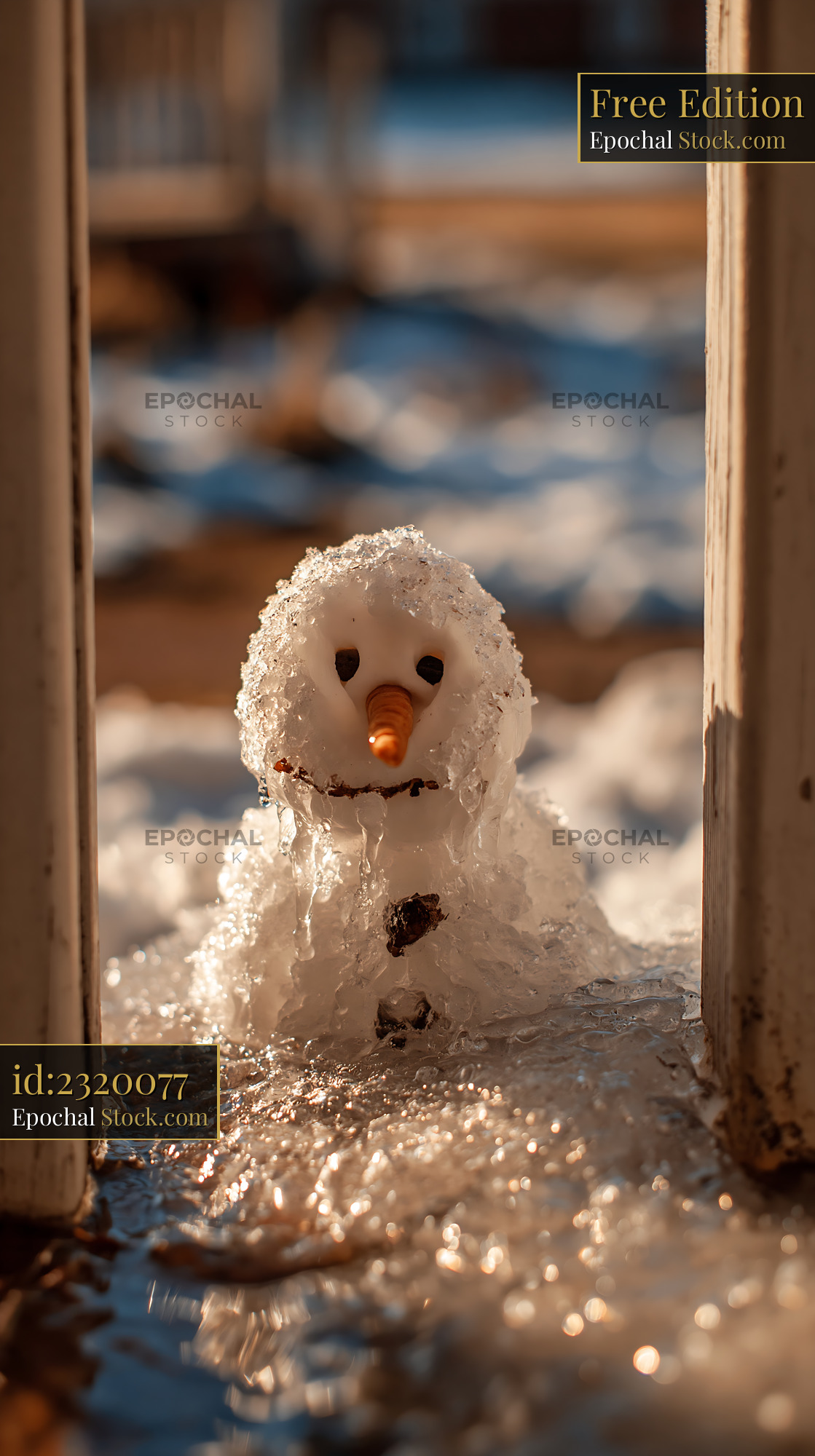 Small melting snowman with carrot nose in warm spring sunlight - stock photo