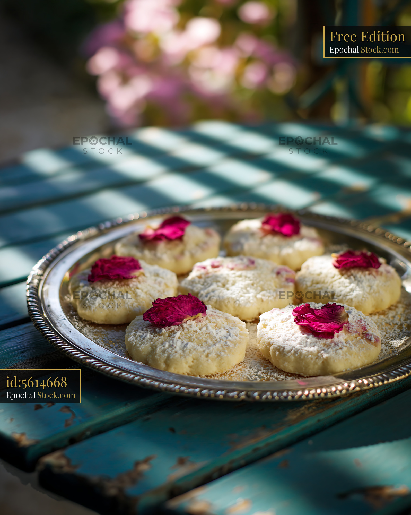 Rose water biscuits with dried petals on a silver tray in the sun - stock photo