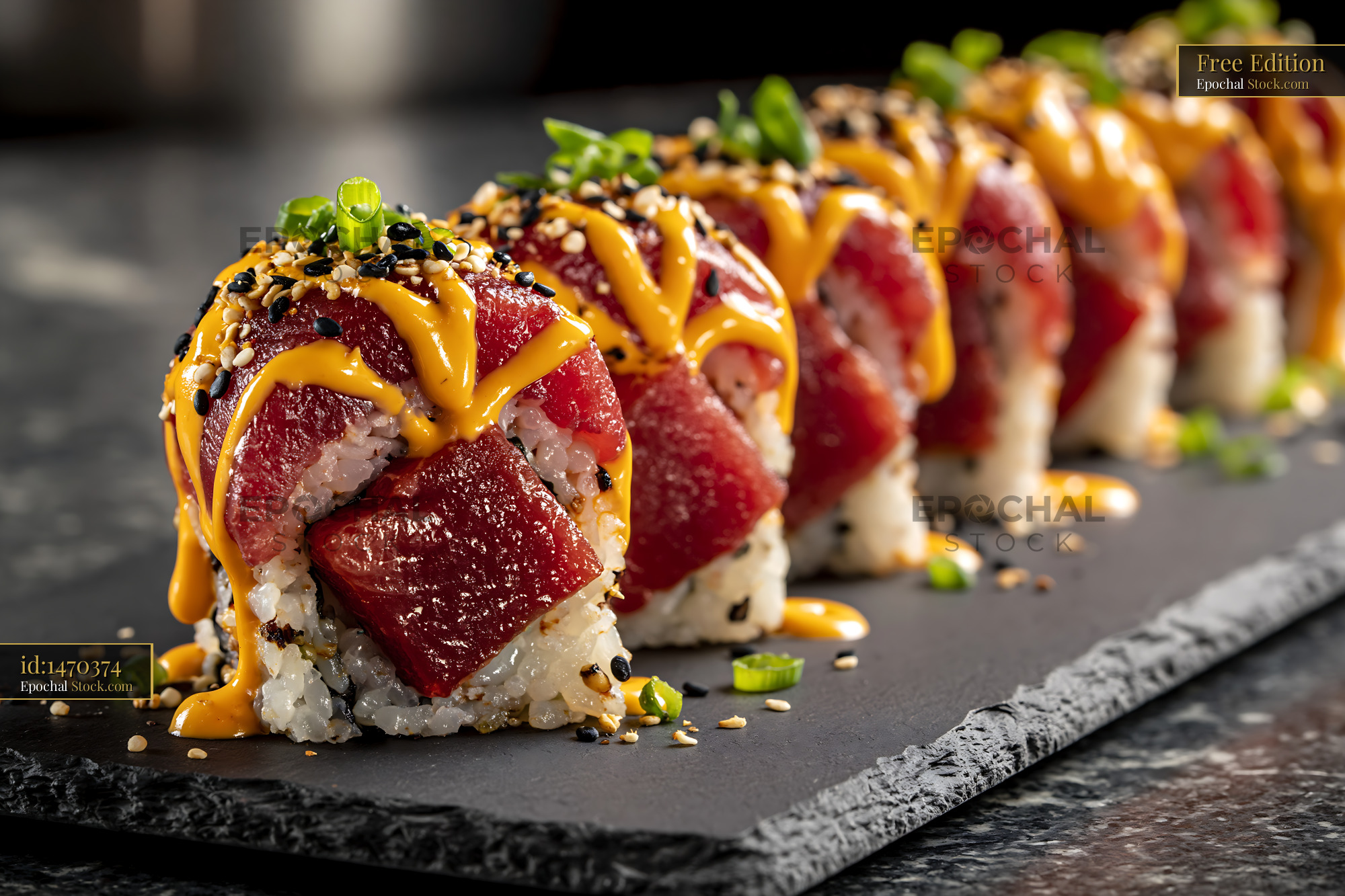 Fresh tuna sushi rolls topped with spicy sriracha mayo on slate - stock photo