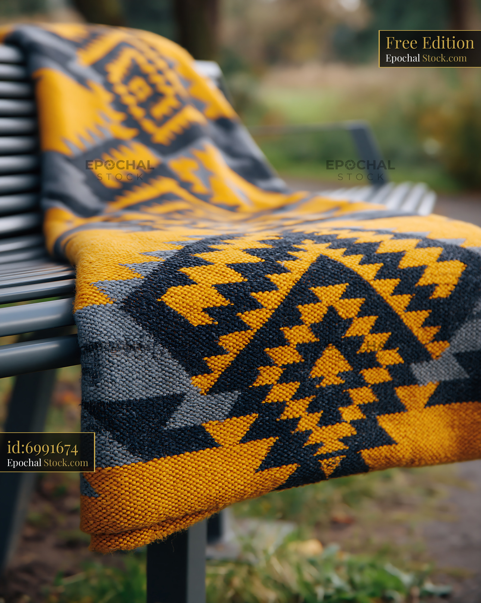 Patterned blanket with geometric design draped over a metal park seat - stock photo