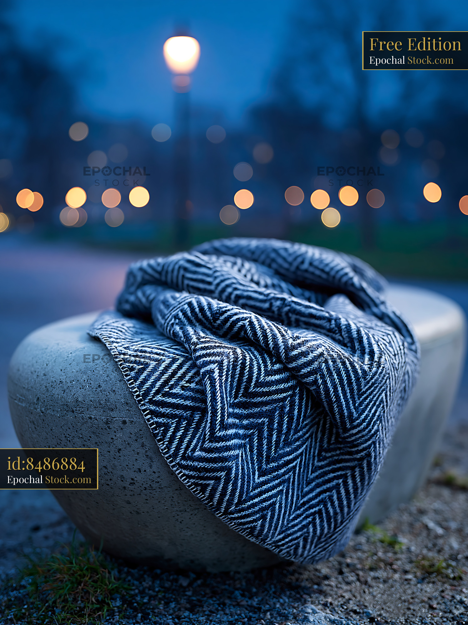 Blue and white striped throw on concrete bench in a park at night - stock photo