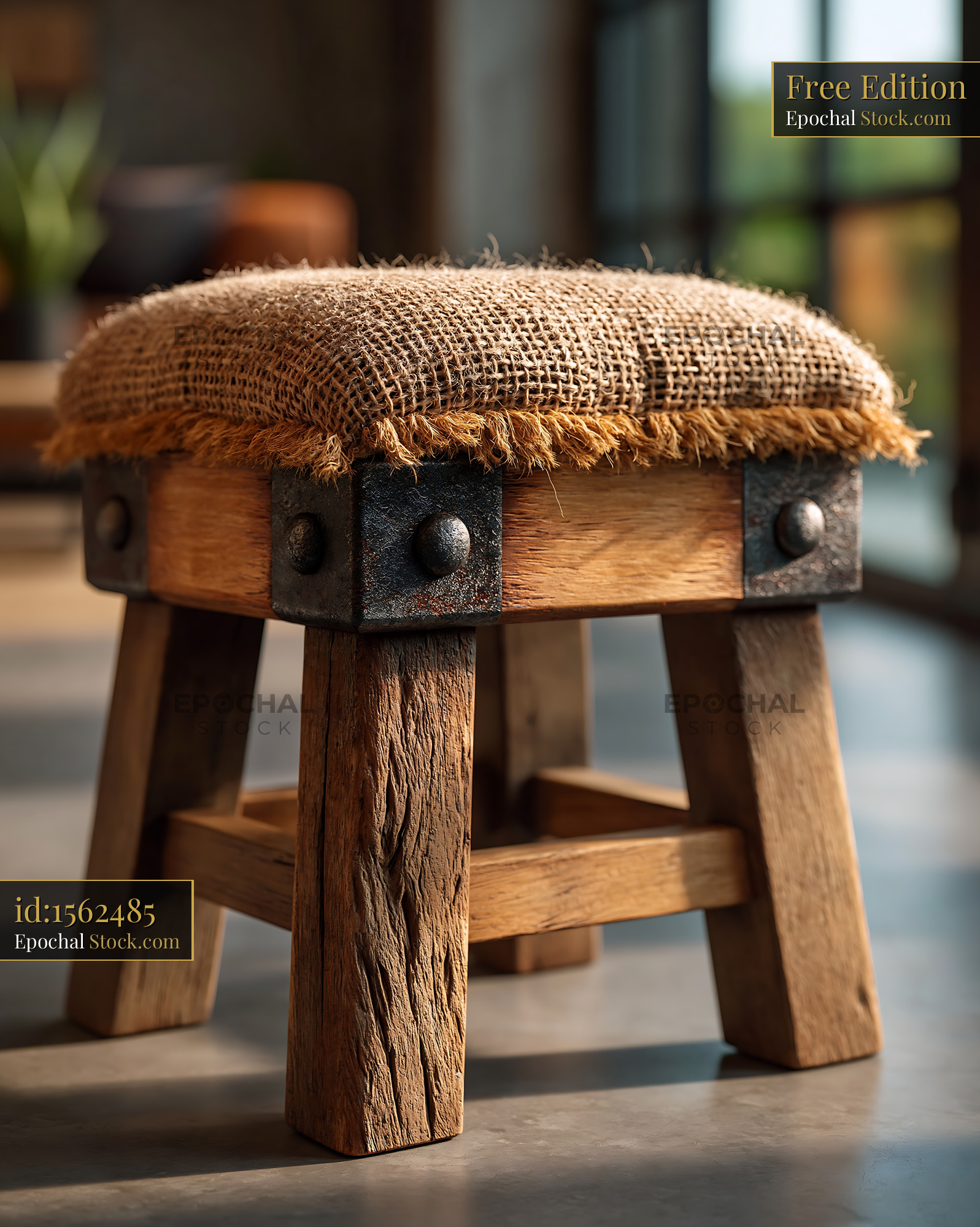Rustic wooden stool with burlap upholstery in a sunlit room - stock photo