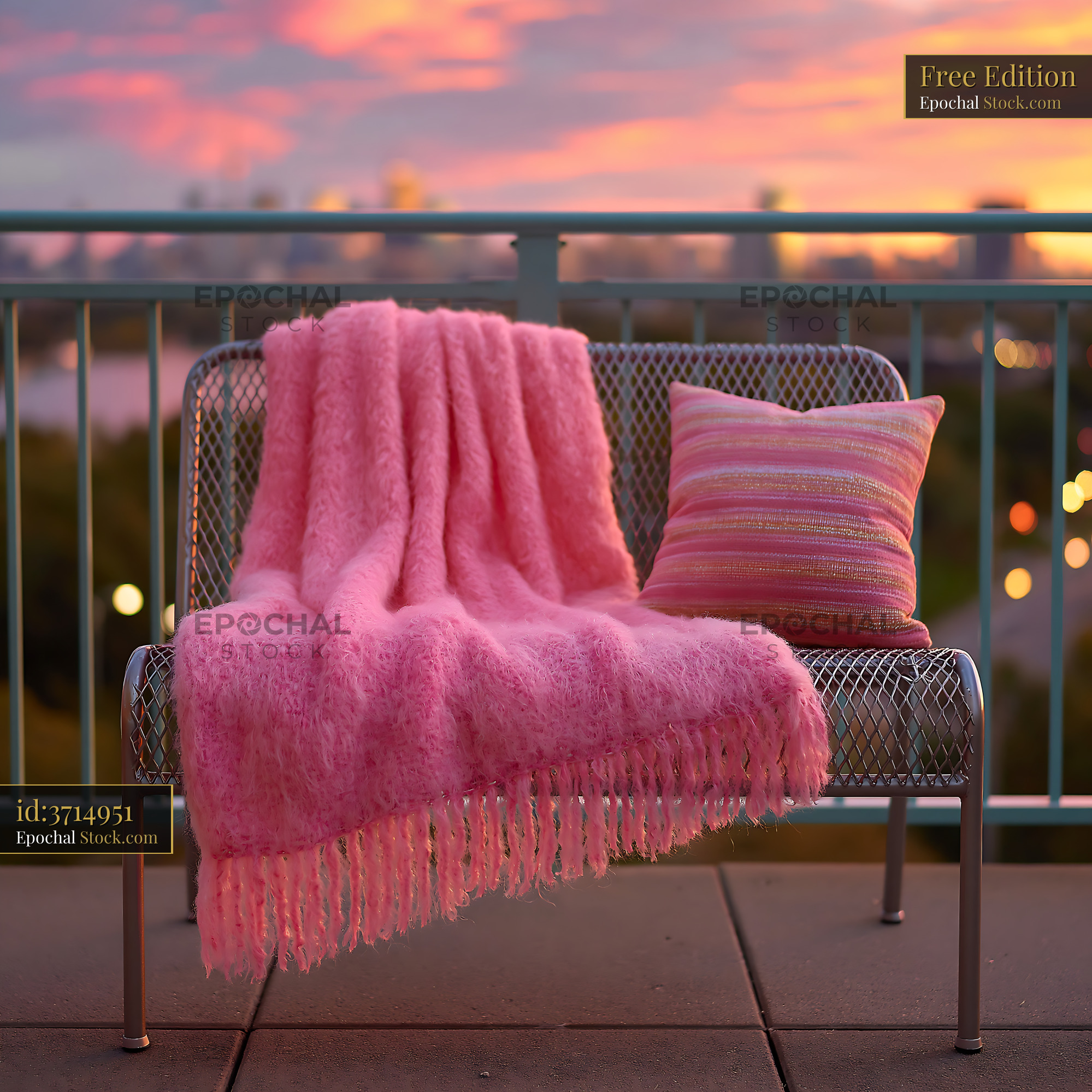 Balcony bench with throw and pillow overlooking a city at sunset - stock photo