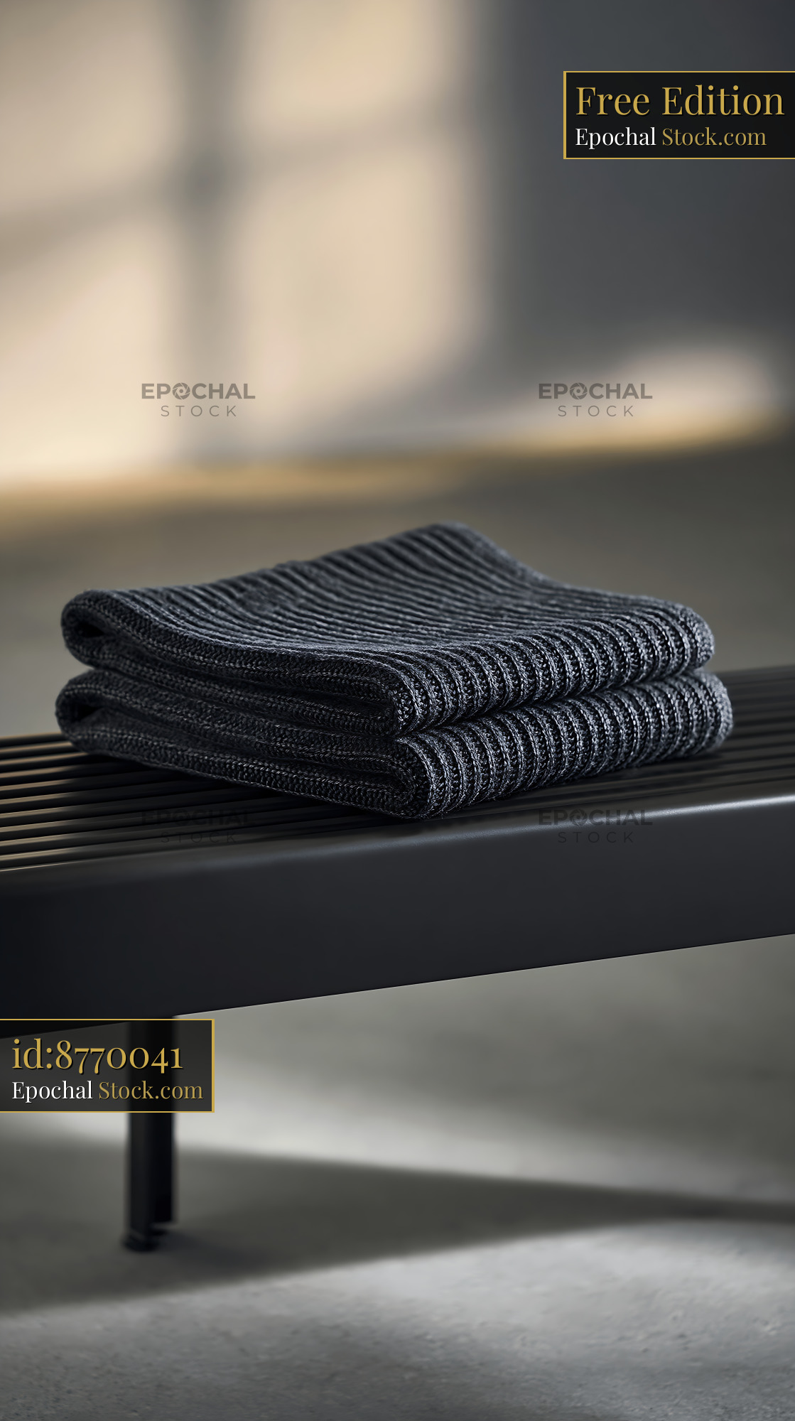 Folded dark grey cashmere throw on a modern black bench - stock photo