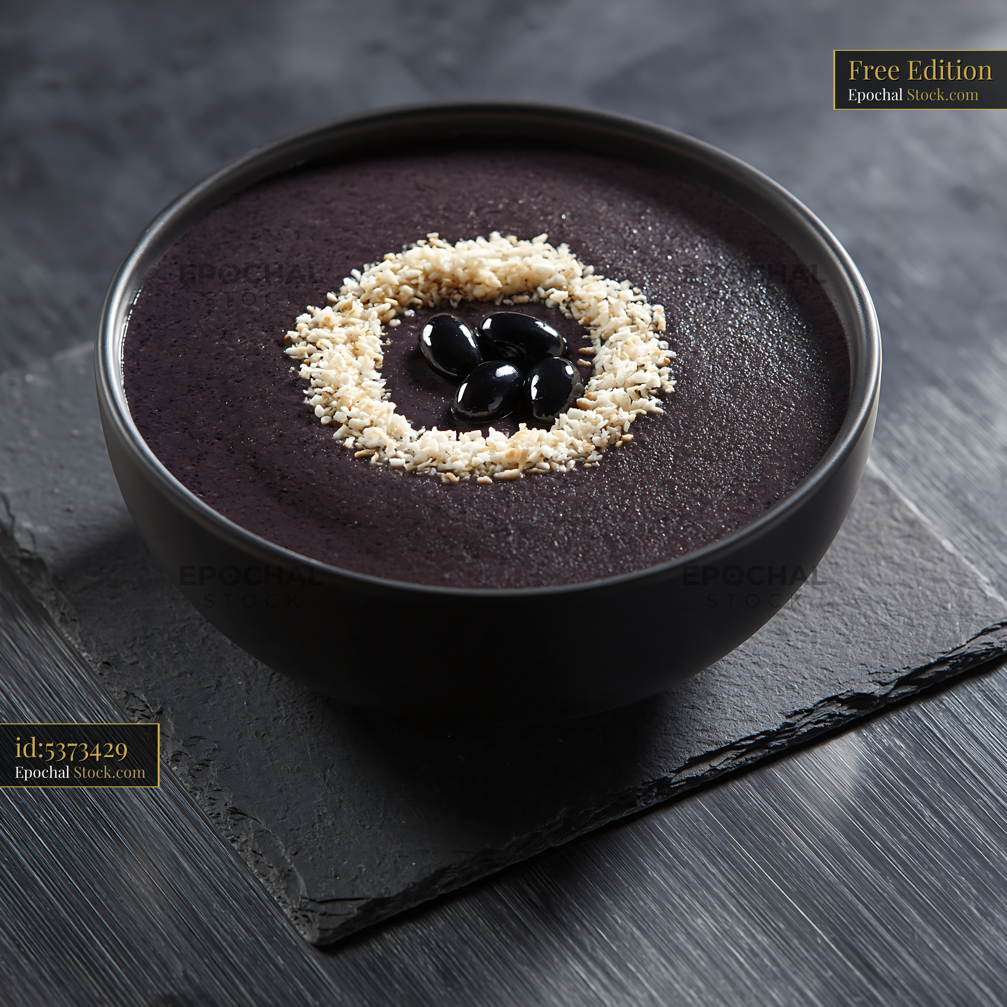 Creamy black bean smoothie bowl with seed garnish on dark slate - stock photo
