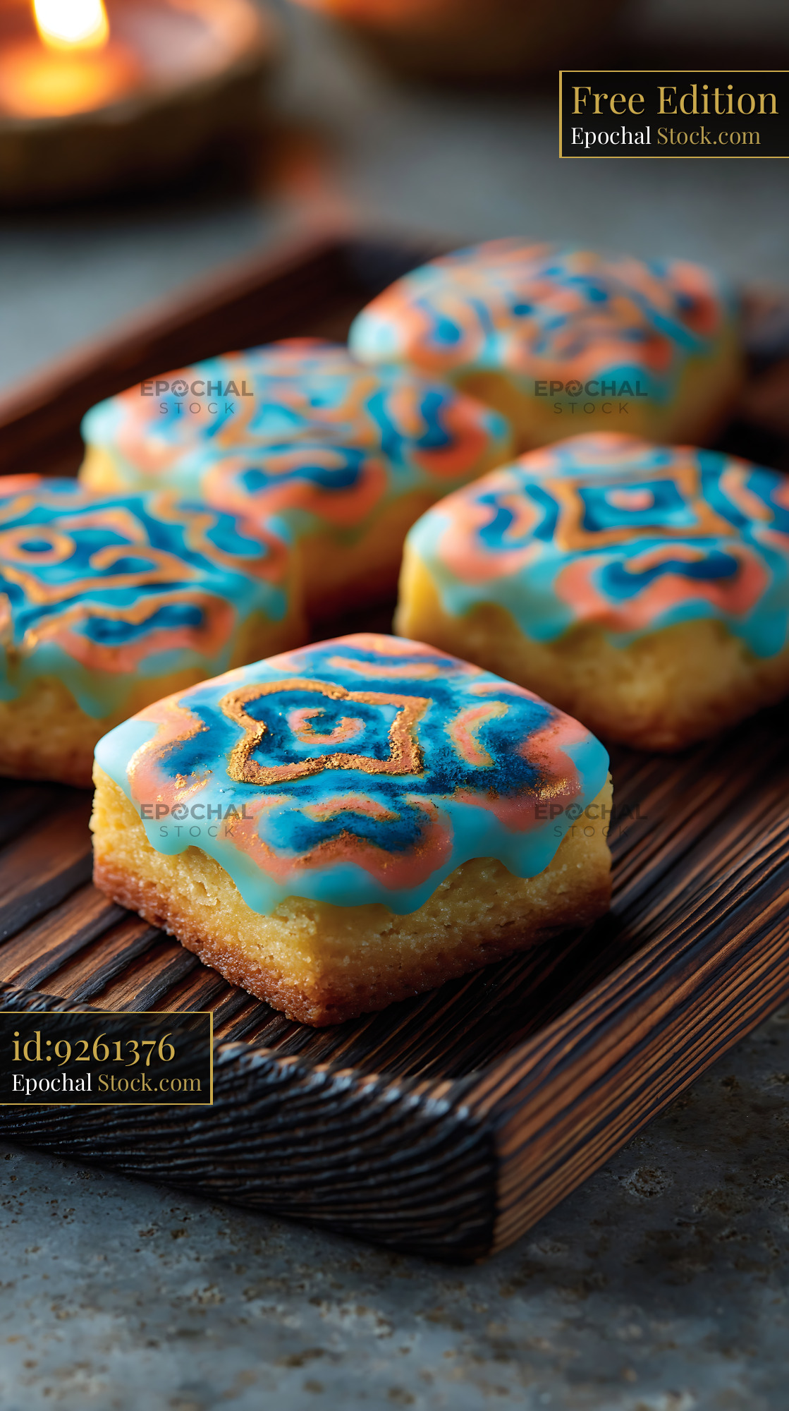 Ornate square pastries with blue and orange icing on wooden tray - stock photo