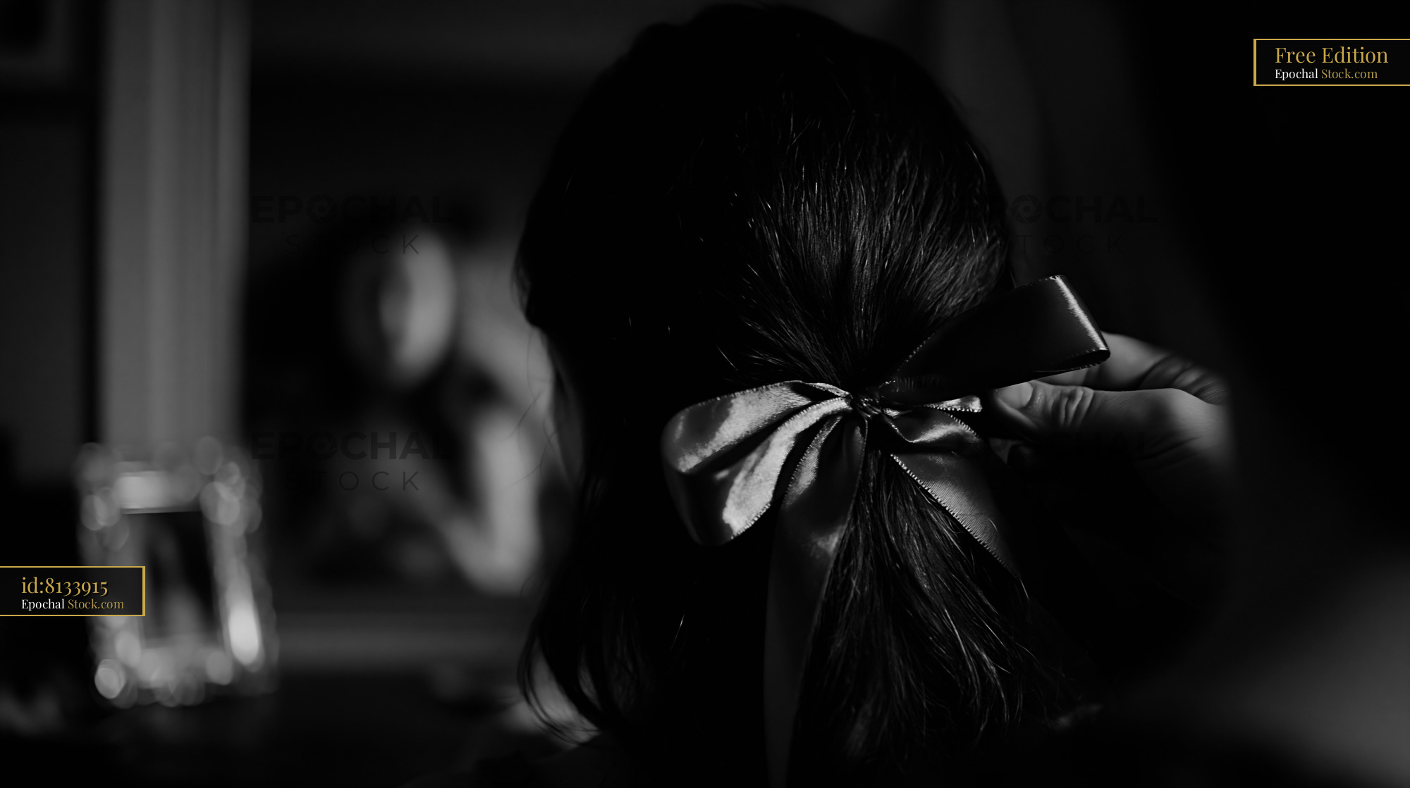 Mother fixing silk ribbon in young daughter's hair before a mirror - stock photo