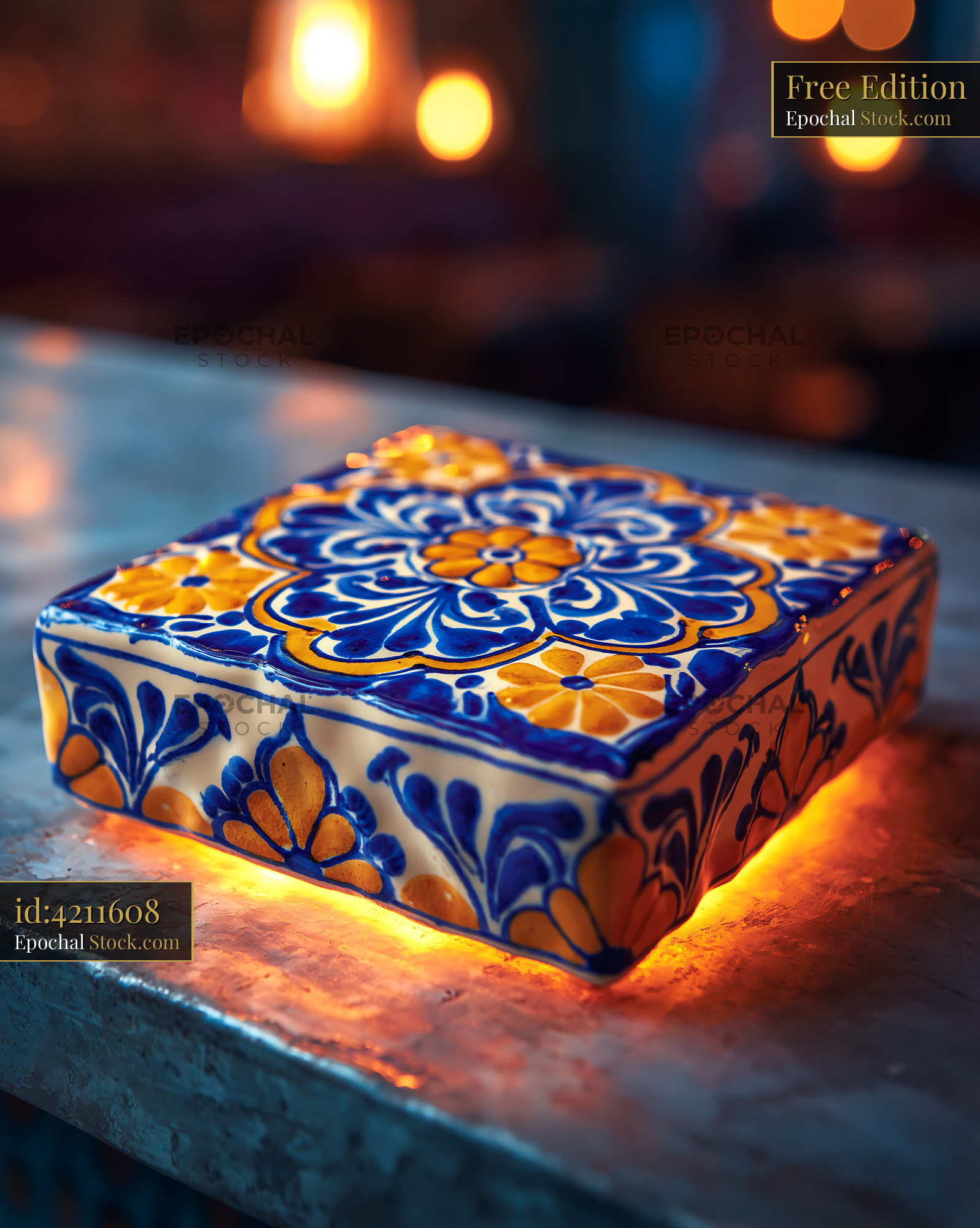 Ornate ceramic tile with floral pattern glowing on a dark surface - stock photo