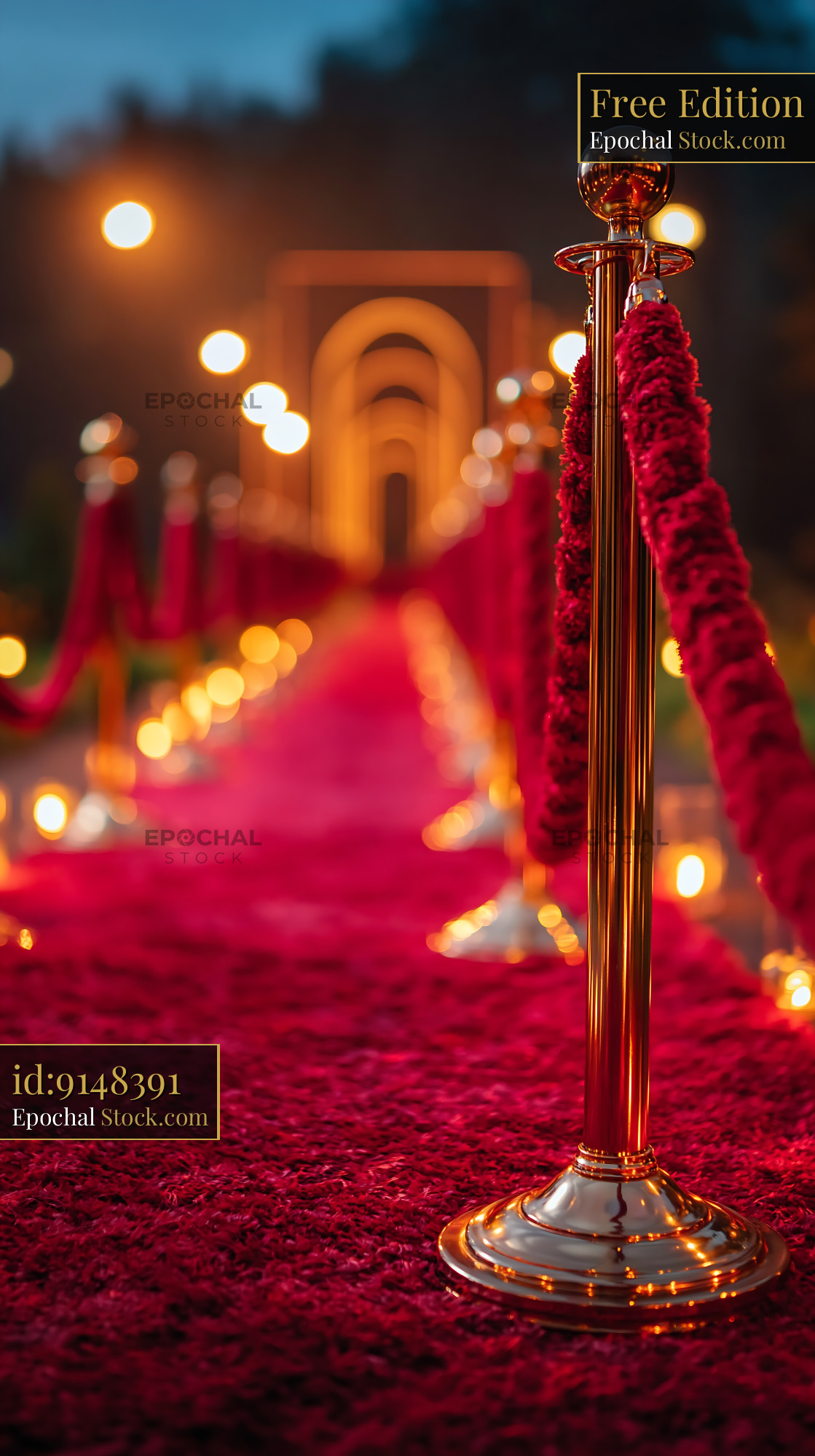 Empty stage with red carpet and gold stanchions under warm lights - stock photo
