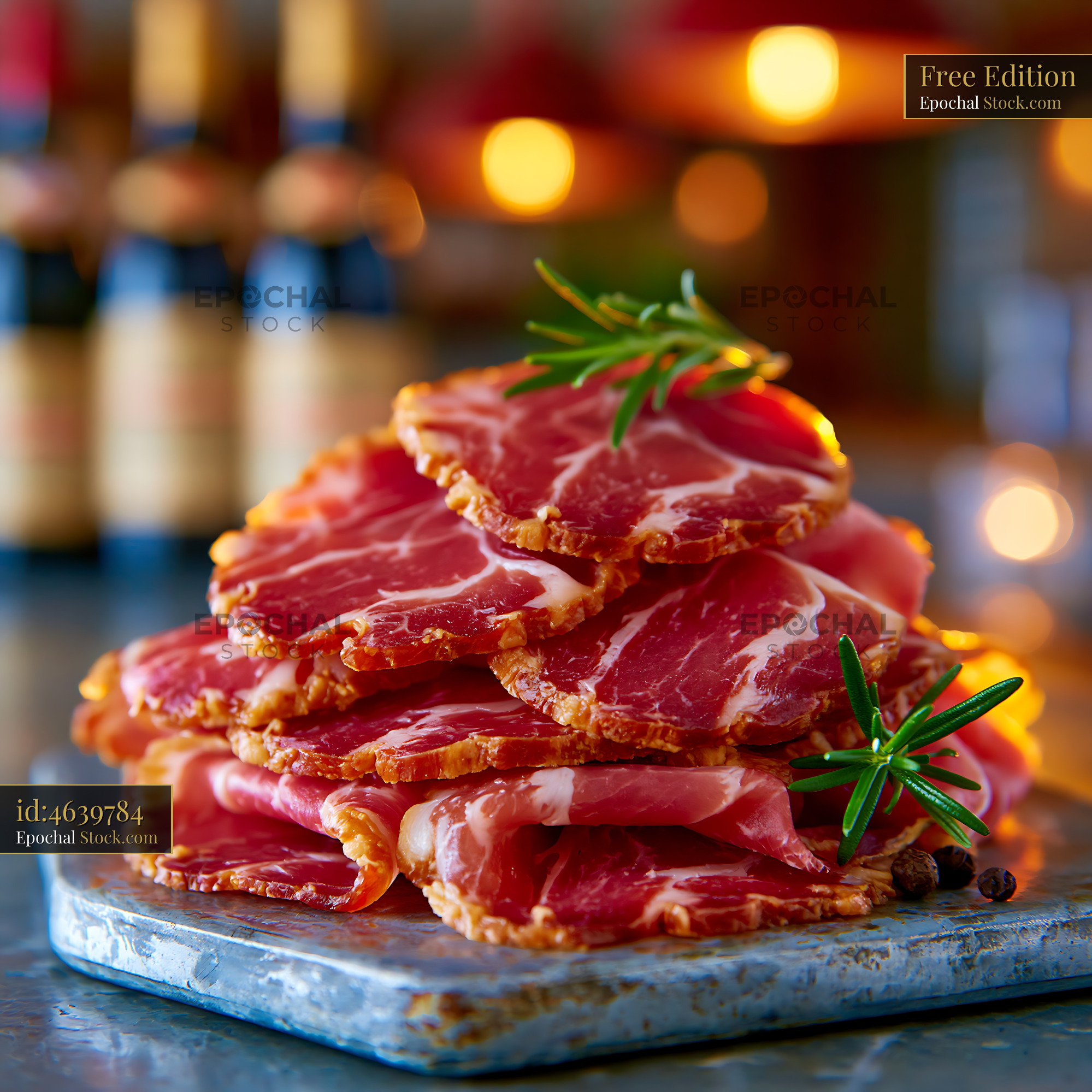 Thinly sliced jambon de bayonne meat with rosemary on stone board - stock photo