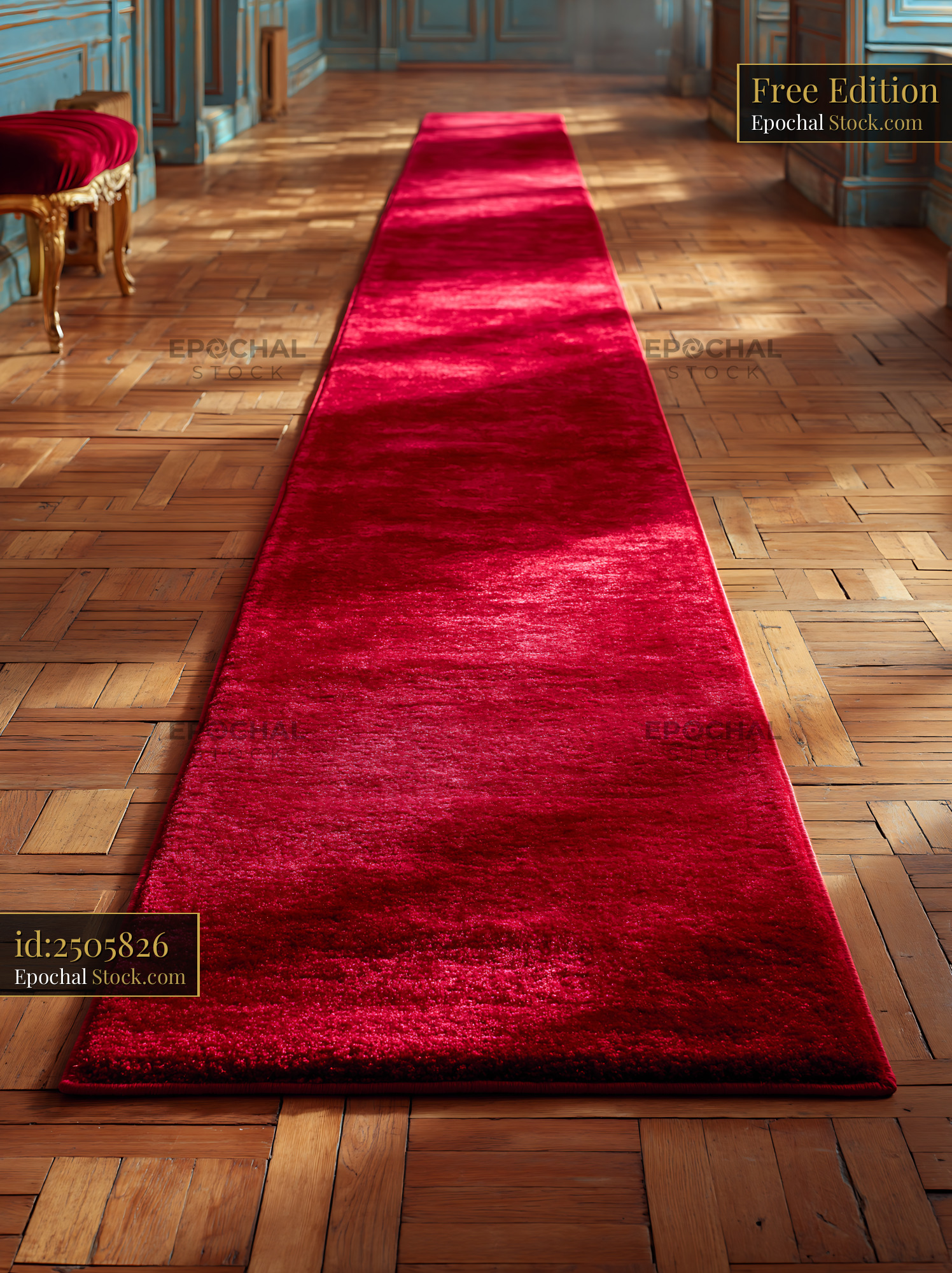 Long red carpet runner on sunlit parquet floor in a grand hallway - stock photo