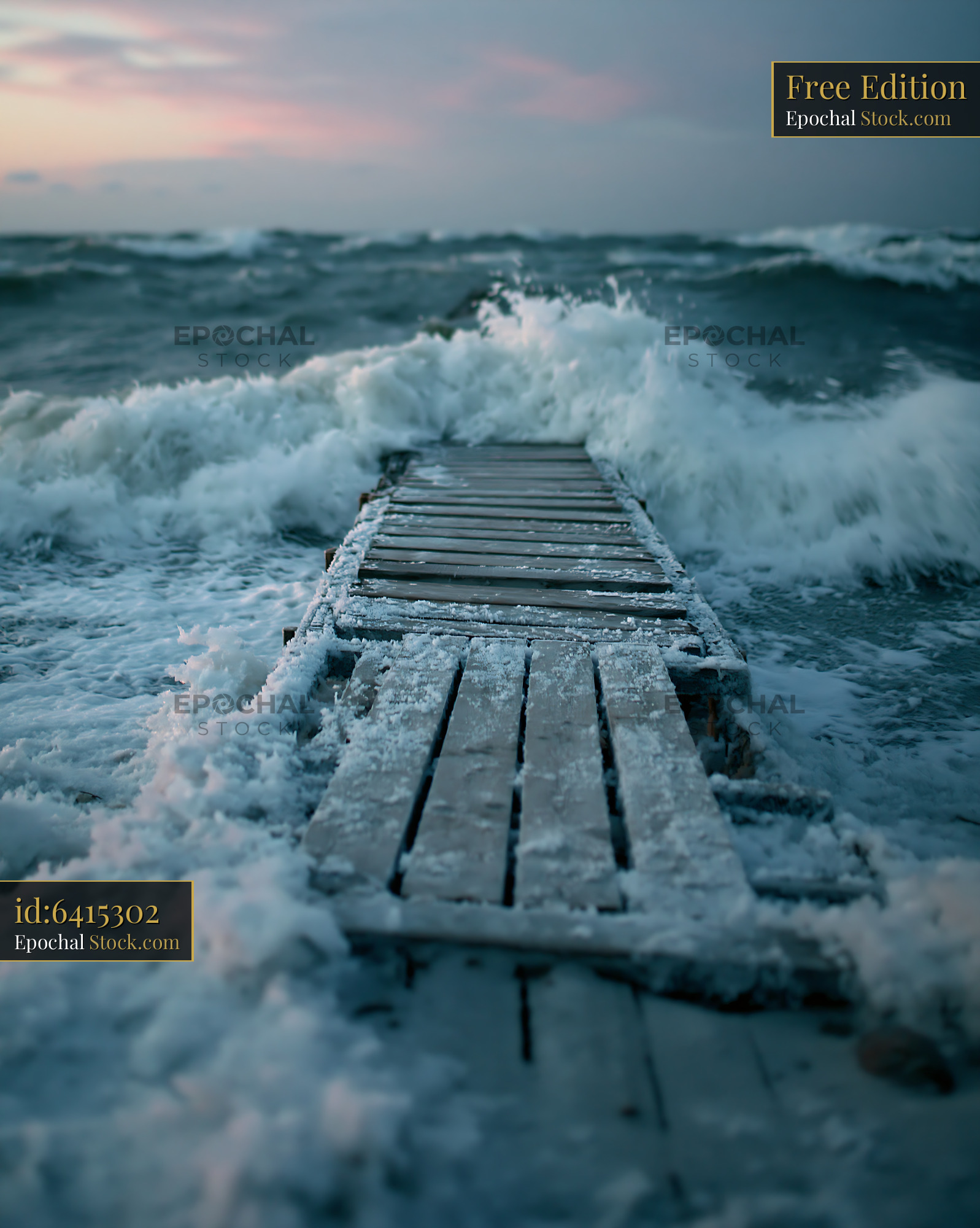 Old wooden pier in a stormy sea during winter dusk with crashing waves